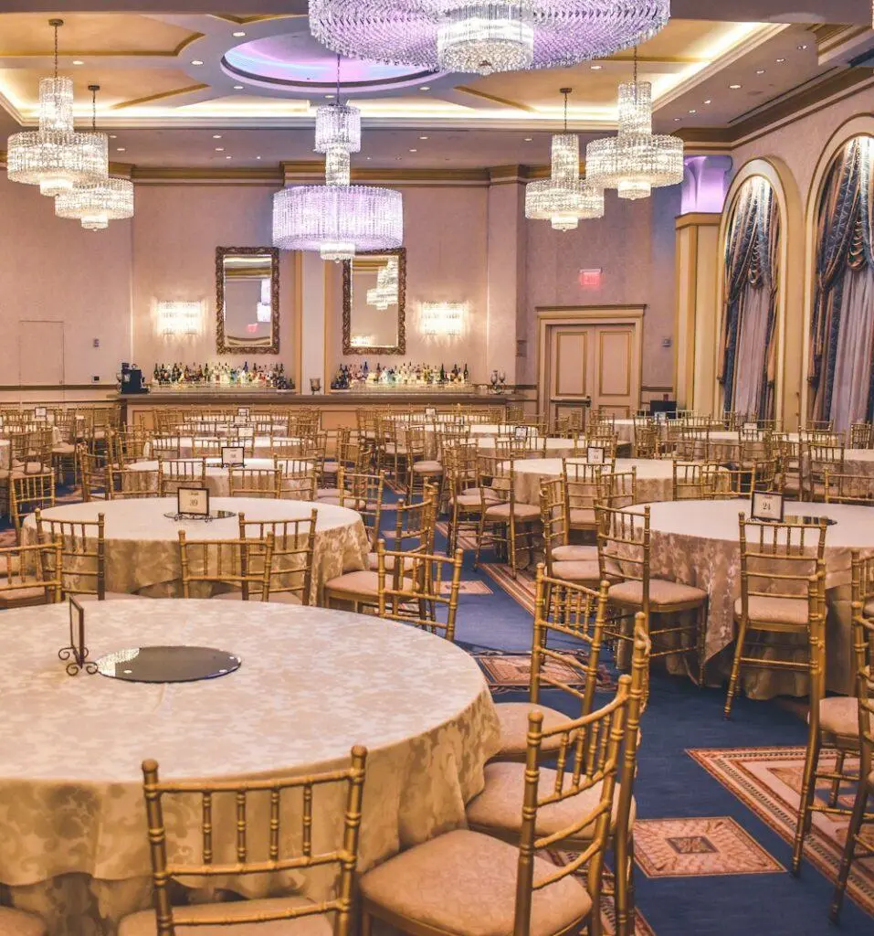 Reception hall with round tables, gold chairs and chandeliers
