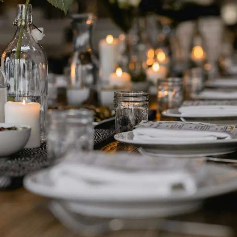 Candlelit table setting with white plates and crystal glassware