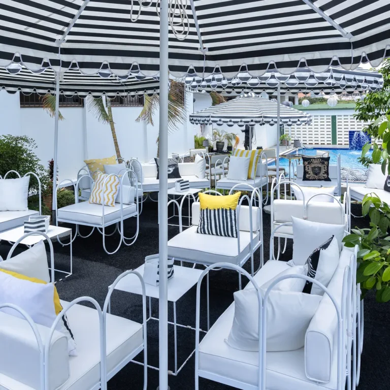 Outdoor lounge with black and white striped parasols and white sofas with yellow and striped cushions